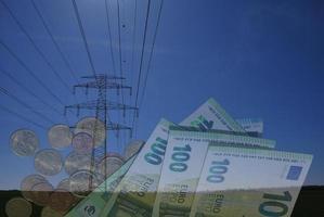 pylône électrique avec ciel bleu et champ vert avec billets et pièces de 100 euros photo