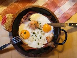 deux œufs frits et du bacon dans une casserole pour le petit-déjeuner en vacances photo