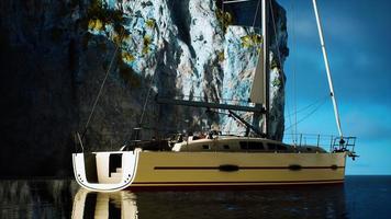 yacht blanc ancré dans une baie aux falaises rocheuses photo