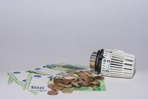 Les prix de l'énergie augmentent et la consommation d'énergie du régulateur thermostatique de chauffage avec 100 billets et pièces en euros en bas photo
