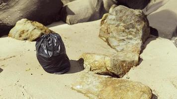 sac poubelle en plastique noir plein de déchets sur la plage photo