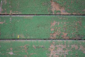 le mur est fait de vieilles planches avec des restes de peinture verte photo