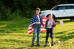 deux frères avec le drapeau américain. vacances en amérique. fiers d'être des enfants du pays. photo