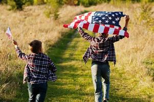 deux frères courant avec le drapeau américain. vacances en amérique. fiers d'être des enfants du pays. photo