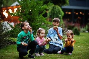 quatre enfants avec des beignets dans la cour du soir. délicieux beignets délicieux. photo