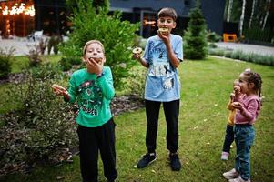 quatre enfants avec des beignets dans la cour du soir. délicieux beignets délicieux. photo