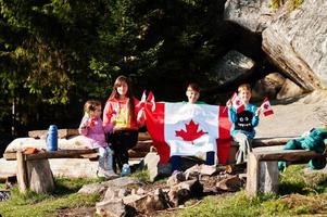 joyeux jour du Canada. la famille d'une mère avec trois enfants organise une grande célébration du drapeau canadien dans les montagnes. photo