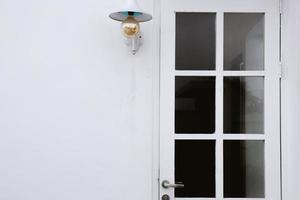 conception de maison extérieure blanche minimaliste avec porte d'entrée blanche avec verre et lampe à ampoule suspendue photo