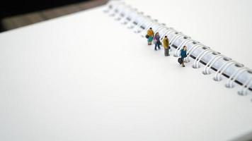 personnes miniatures en groupe marchant sur un livre blanc blanc. concept d'entreprise avec espace de copie et espace blanc pour votre texte ou votre conception photo