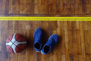 vue de dessus de chaussures et de basket-ball sur un terrain de basket en bois photo