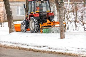 le nettoyeur de tracteur compact routier nettoie la neige sur le trottoir. photo