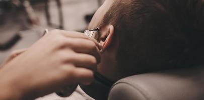 jeune homme se fait couper la barbe par un coiffeur photo