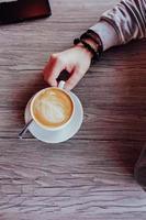 la main de l'homme à côté d'une tasse de café photo