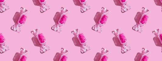 boîte transparente en forme de bonbon avec des sucettes au coeur doux avec une ombre dure sur l'espace de copie de fond rose. le concept de la saint valentin, fête des mères. bannière. schéma photo