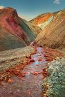 emblématique arc-en-ciel coloré volcanique mont brennisteinsalda vague de soufre et ruisseau dans la région montagneuse de landmannalaugar en islande au coucher du soleil et au ciel bleu. photo