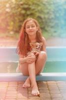 vacances avec un animal de compagnie. jolie fille de 10 ou 11 ans avec son chien au bord de la piscine. photo