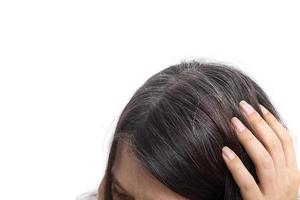 main de femme sur la tête avec des cheveux gris sur fond blanc. le concept des premiers cheveux gris. photo