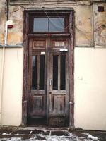 vieille porte en bois marron dans un bâtiment en béton léger avec des fils et de la neige dans les escaliers photo