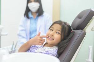 une petite fille mignonne ayant des dents examinées par un dentiste dans une clinique dentaire, un contrôle des dents et un concept de dents saines photo