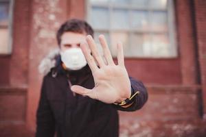 homme portant un masque de protection médicale montrant un geste d'arrêt photo