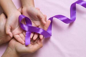 mains tenant des rubans violets concept de la journée mondiale du cancer photo