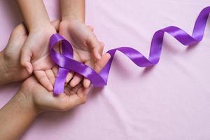 mains tenant des rubans violets concept de la journée mondiale du cancer photo