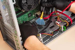 l'assistant répare l'ordinateur personnel avec des outils et des mains. démontage de l'ordinateur en pièces détachées photo