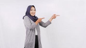 Jeune femme asiatique pointant sur le côté isolé sur fond blanc photo