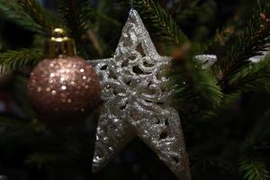 une étoile argentée brillante parmi les aiguilles sur un sapin de noël vert avec des jouets. fond festif. photo