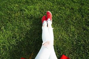 jambes féminines en baskets sur fond d'herbe verte photo