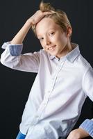 un mec blond en chemise blanche redresse ses cheveux sur un fond noir photo