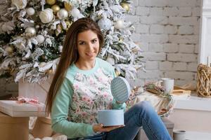 belle femme ouvre des cadeaux à la maison au tre de noël photo