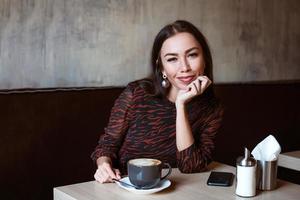 jeune femme à une table dans un café avec du café photo