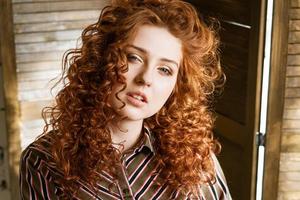 portrait d'une jeune femme rousse heureuse près d'une fenêtre photo