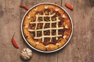 vue de dessus de pizza au boeuf et fromage à la crème entouré de piments et d'ail servi sur table en bois photo