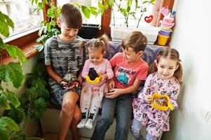 quatre enfants tenant leurs animaux de compagnie préférés sur les mains. enfants jouant avec hamster, tortue à la maison. photo