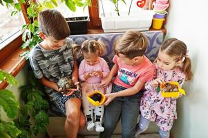 quatre enfants tenant leurs animaux de compagnie préférés sur les mains. enfants jouant avec hamster, tortue à la maison. photo