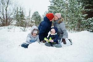 père et mère avec deux filles dans la nature hivernale. à l'extérieur dans la neige. photo