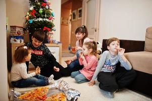 famille heureuse avec quatre enfants mangeant de la pizza à la maison. photo