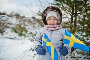 petite fille scandinave avec le drapeau de la suède dans le paysage suédois d'hiver. photo