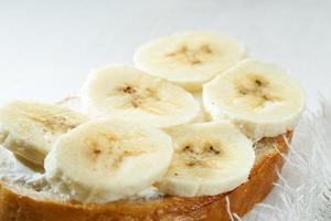 sandwich aux tranches de banane se bouchent sur une table en bois blanche. photo