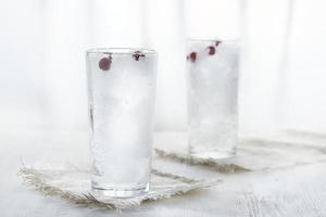 deux verres avec de la glace pilée et des baies de cassis sur fond blanc en flou. photo