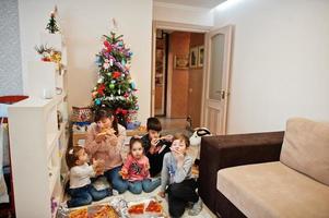 famille heureuse avec quatre enfants mangeant de la pizza à la maison. photo