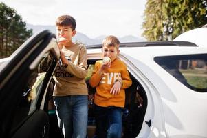 deux frères mangent des pommes à l'intérieur du véhicule. voyager en voiture dans les montagnes, concept d'ambiance. photo