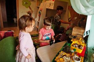 quatre enfants tenant leurs animaux de compagnie préférés sur les mains. les enfants jouent avec le hamster, la tortue et les perroquets à la maison. photo