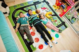 famille heureuse s'amusant ensemble, quatre enfants jouant au jeu twister à la maison. photo