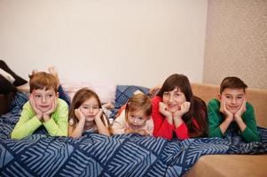une grande famille heureuse s'amuse ensemble dans la chambre. grand concept de matinée familiale. mère de quatre enfants porte un pyjama au lit à la maison. photo