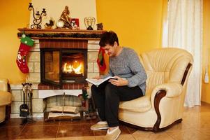homme à la maison près d'une cheminée dans un salon chaleureux le jour de l'hiver. photo