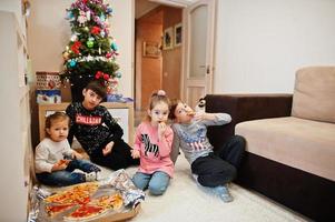 famille heureuse avec quatre enfants mangeant de la pizza à la maison. photo