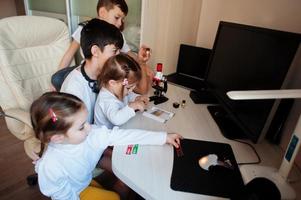 enfants utilisant un microscope apprenant des cours de sciences à la maison. photo